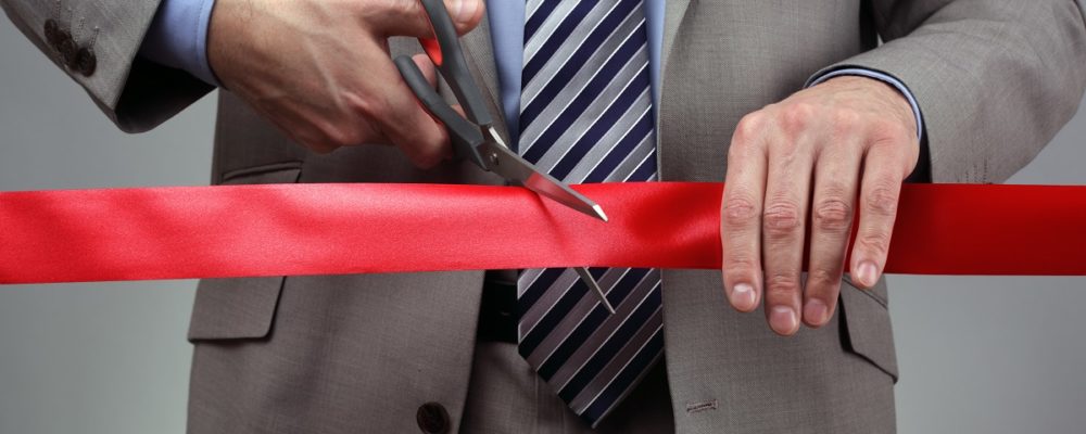 Man cutting a ribbon for his new venture