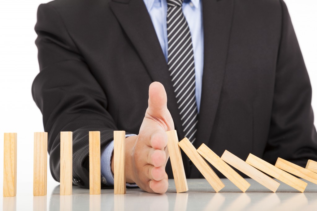 Businessman hand stopping domino