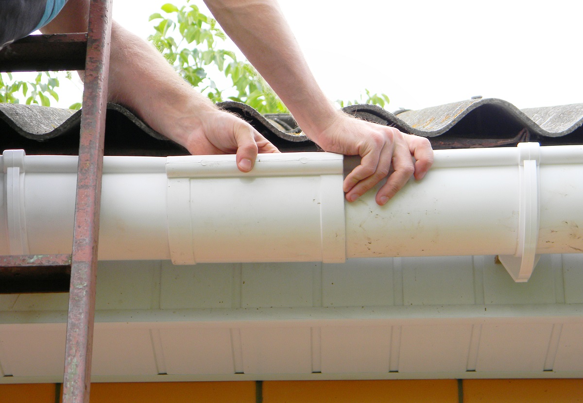 man repairing a home's gutter