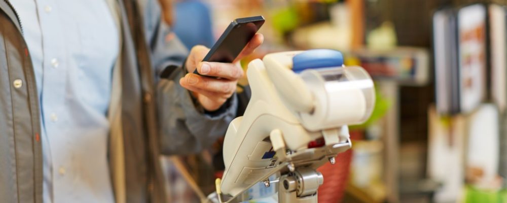 Man paying wireless with his smartphone at supermarket checkout