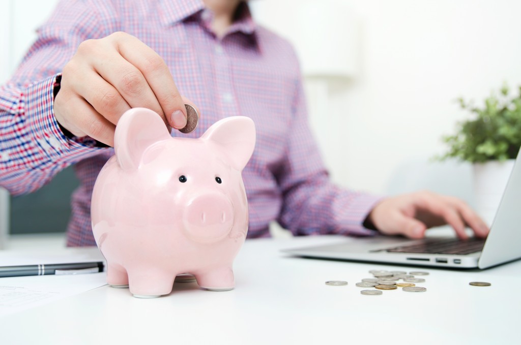 person putting coin in the piggy bank