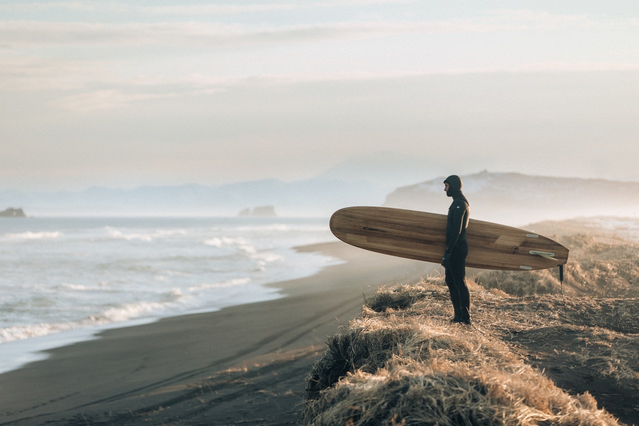 man holding surfboard looking at the ocean