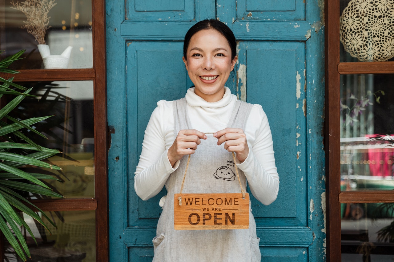 woman holding come in we're open sign