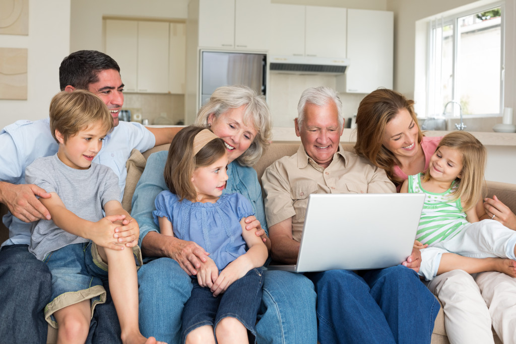 Smiling multigeneration family using laptop in living room